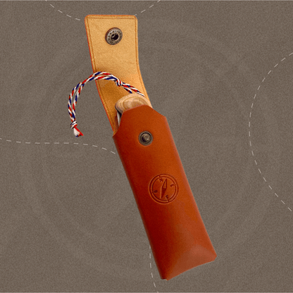 Étui artisanal ouvert laissant apparaître le manche du couteau et sa dragonne tricolore française.